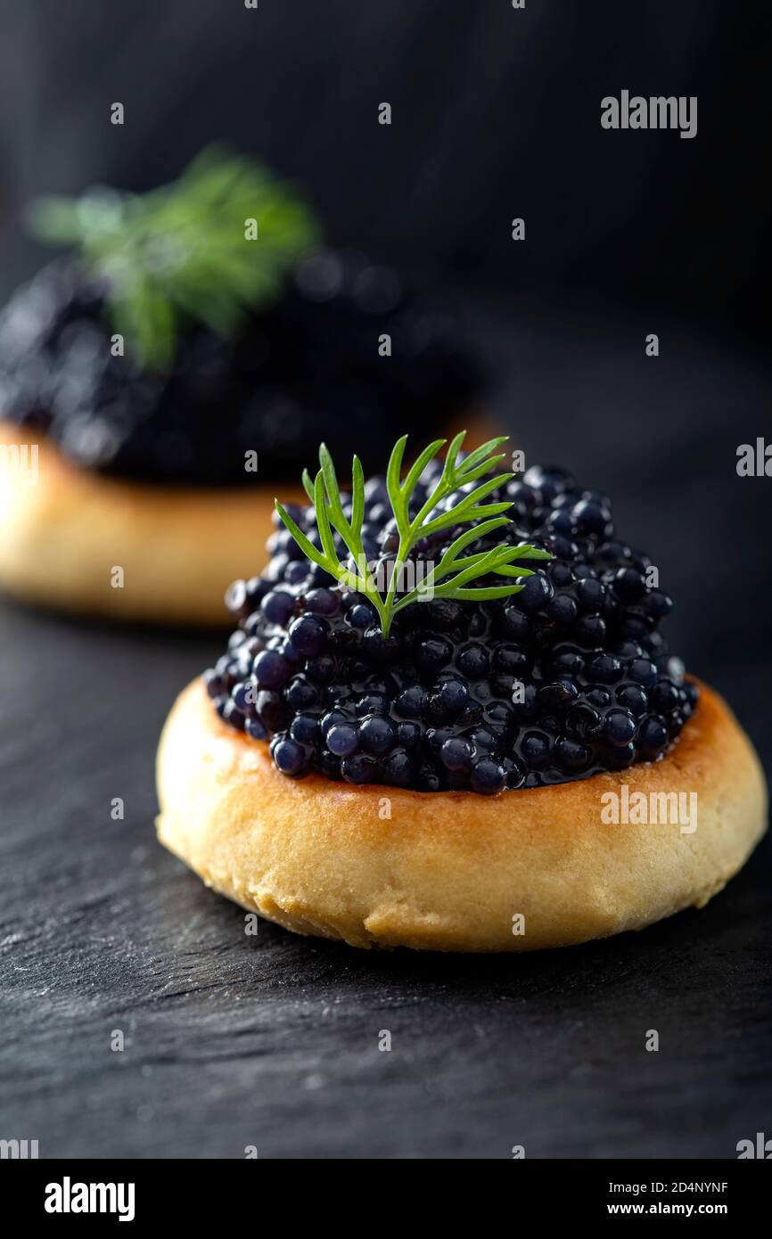 Crackers with black caviar on dark slate Stock Photo