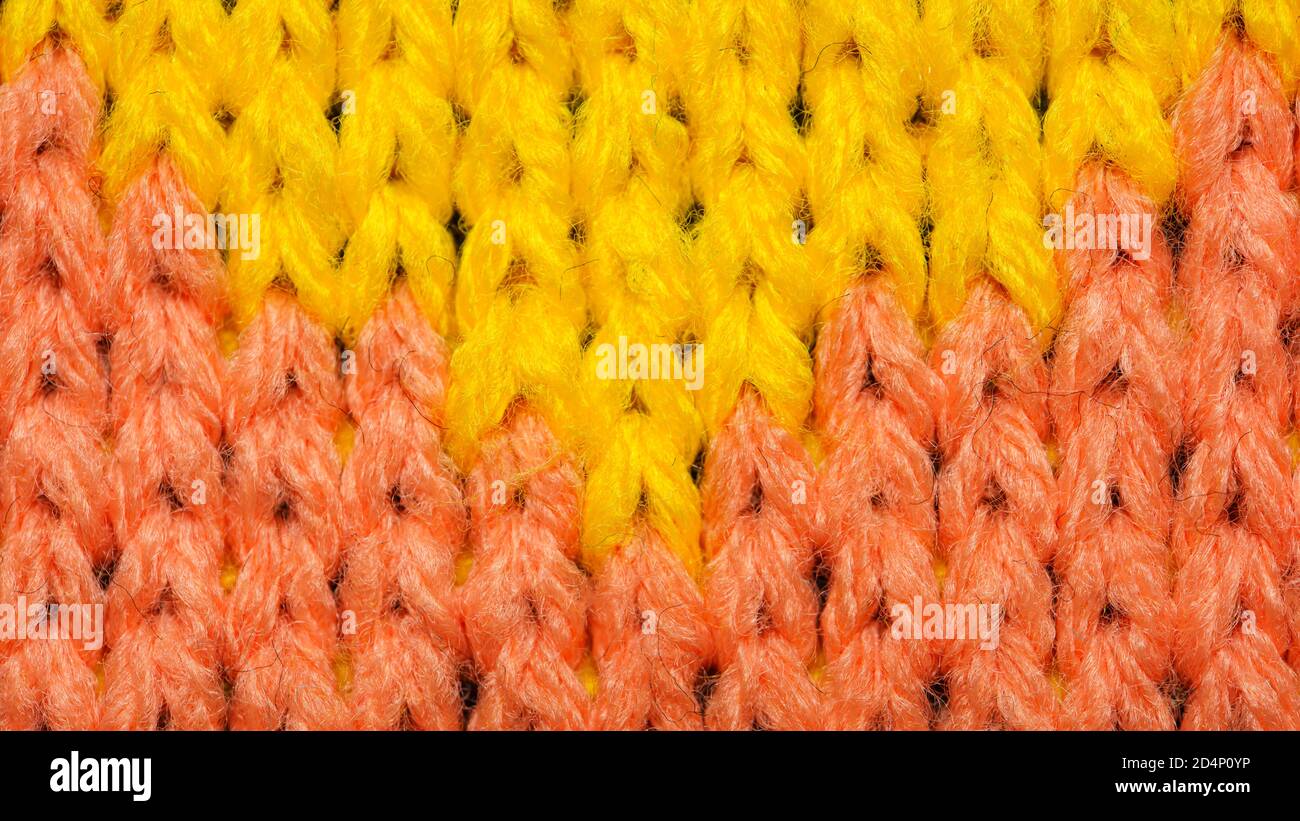 Yellow and red synthetic knitted fabric close up. Knitted fabric texture. Multicolor patterned knitted fabric texture. Background Stock Photo