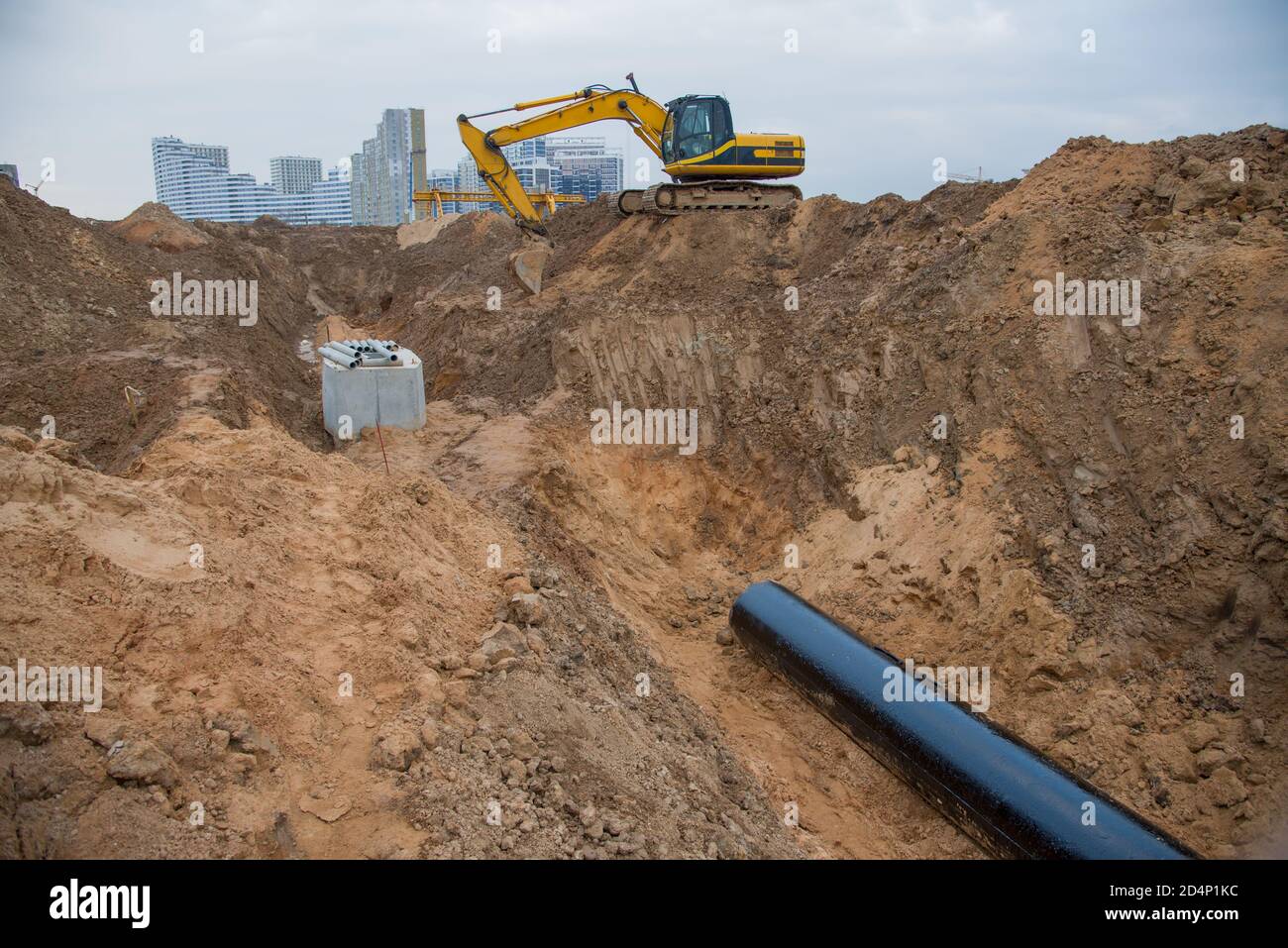 Excavator during laying drain pipes and concrete manholes for