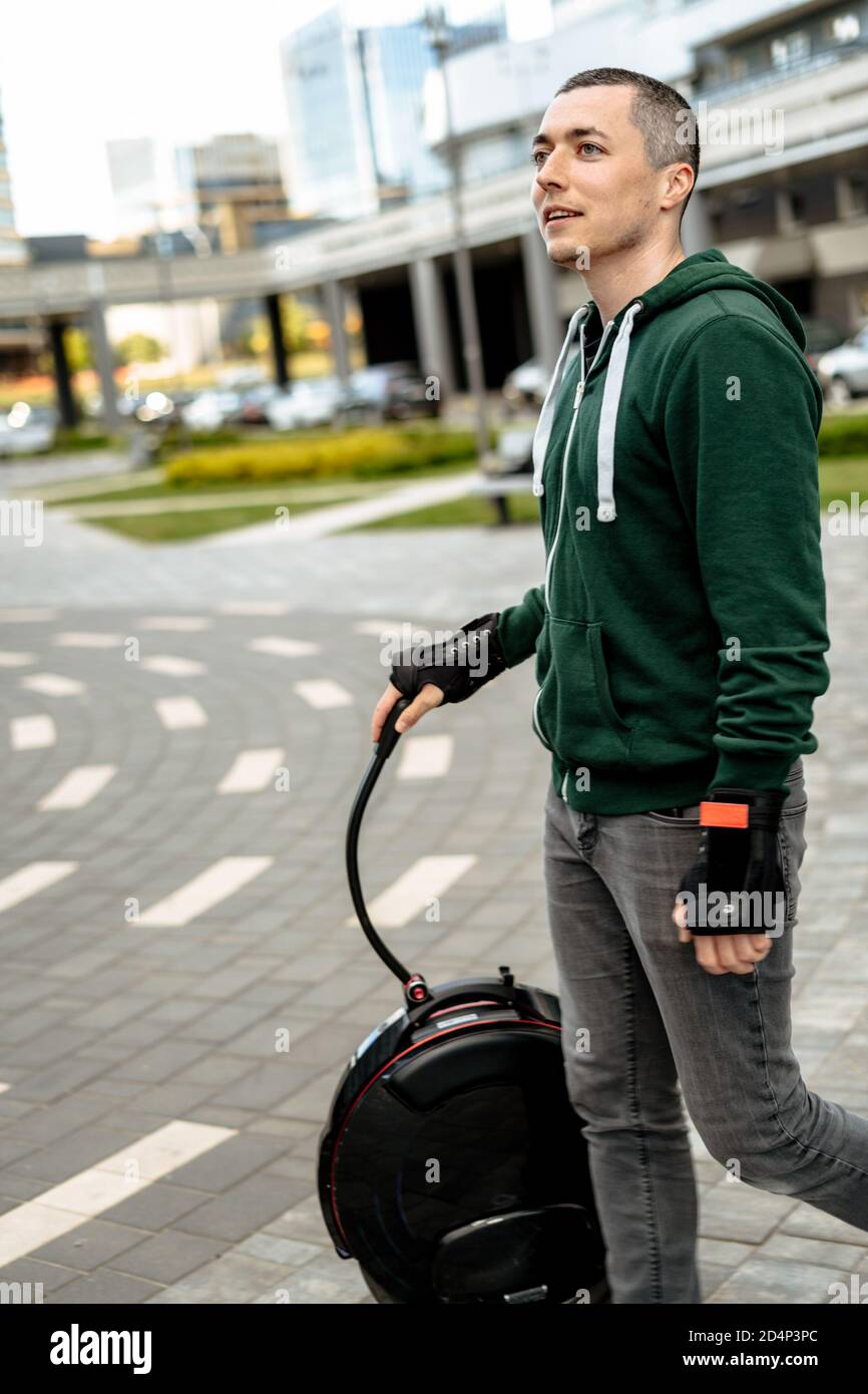 Man transports aunicycle on street, electric unicycle close up. Stock Photo