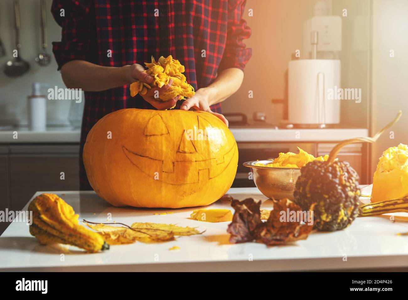 woman prepare pumpkin for halloween holiday decoration remove seeds at home kitchen Stock Photo