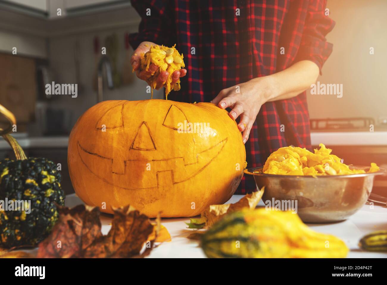woman prepare pumpkin for halloween holiday decoration remove seeds at home kitchen Stock Photo