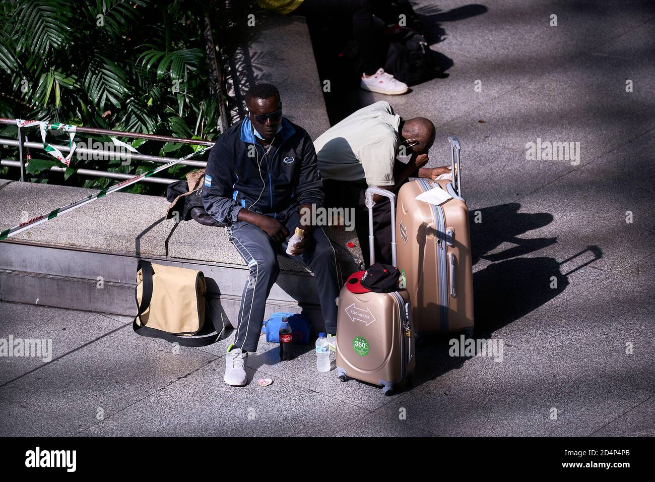Passengers with their luggage waiting at the Madrid Atocha railway station.The government of Spain has declared the state of alarm after the failed negotiations with the government of the Community of Madrid, so this state of alarm is the way to reduce the transmission of the virus in Madrid, closing 10 municipalities of the region. Stock Photo