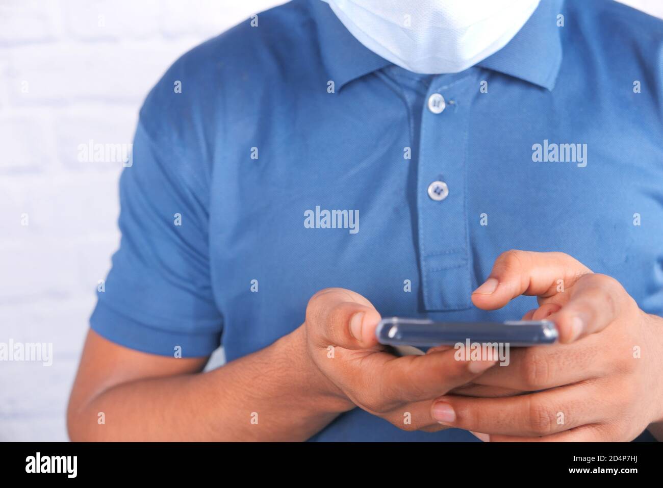 young man with face mask using smart phone indoor  Stock Photo