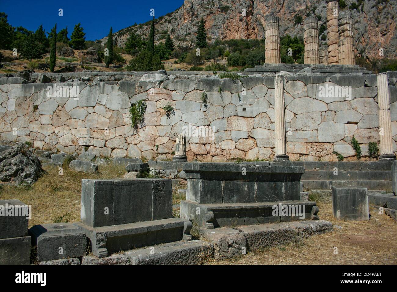 View of the sanctuary of Apollo in Delphi. In the background is the Temple of Apollo and the Stoa of the Athenians. Stock Photo
