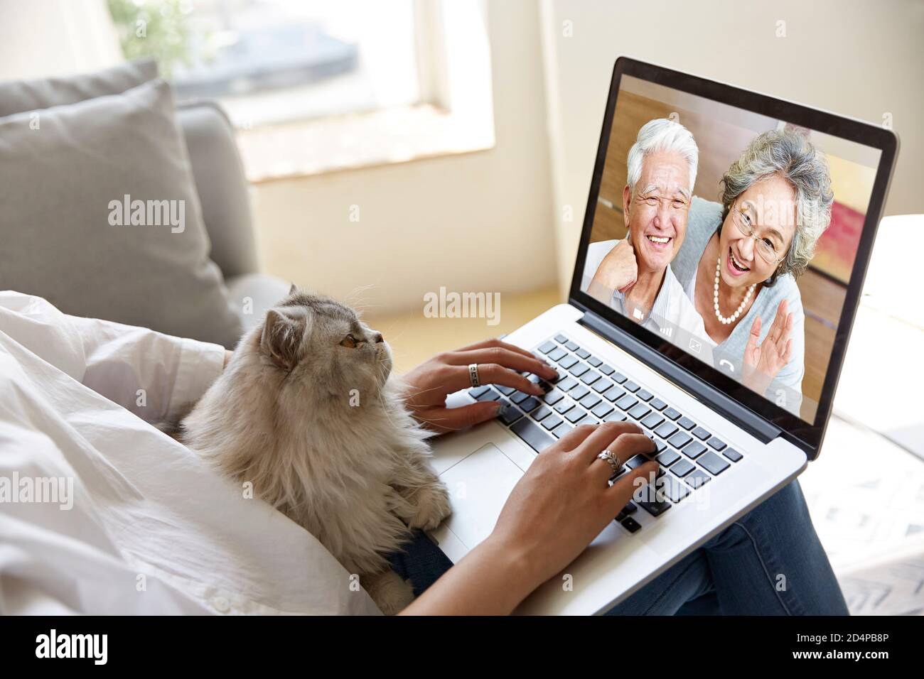 young asian woman video chatting with senior parents using laptop computer Stock Photo