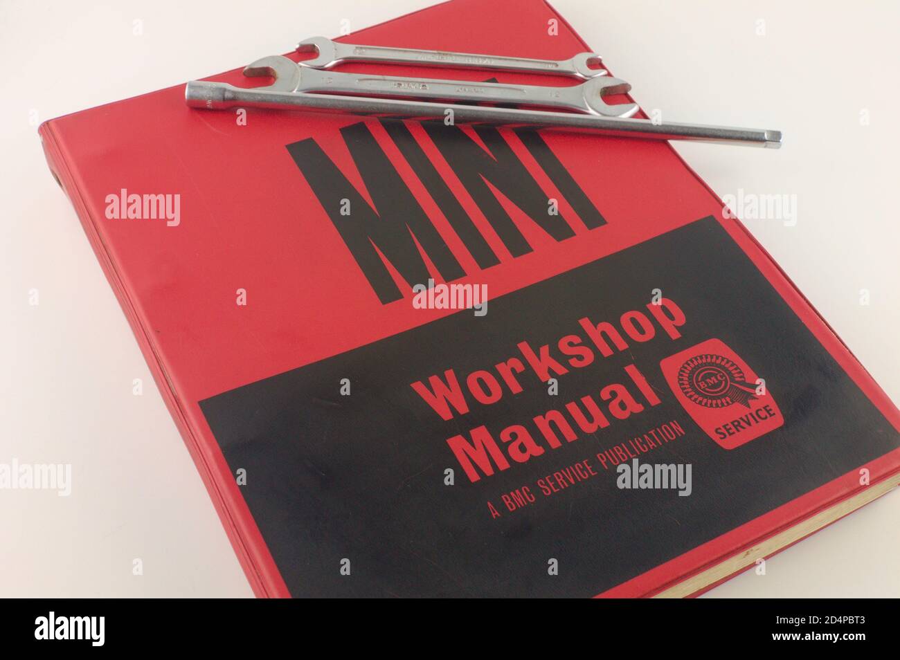 Vintage red and black Mini official work shop manual, BMC service manual with spanners isolated on white background Stock Photo