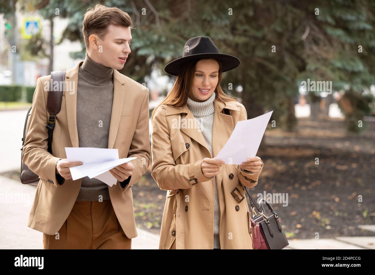 Two young colleagues in elegant casualwear reading papers and discussing them Stock Photo