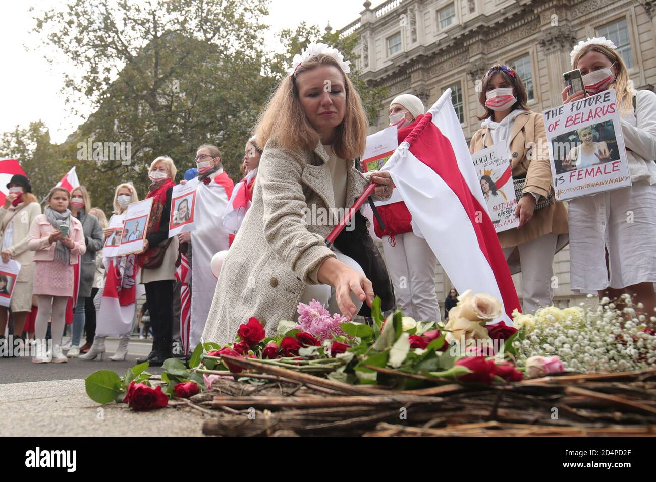 Women lay flowers at the Monument to the Women of World War II in Whitehall, central London, following a march to show solidarity with the women of Belarus. Stock Photo