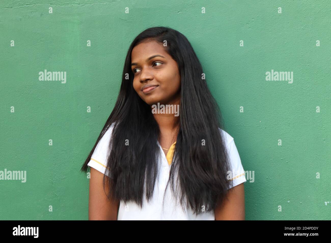 The green wall behind a lonely girl with black hair. Stock Photo