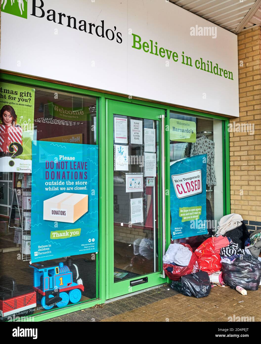 'Do not leave donations while we are closed' notice in the window of a Bernardo's shop (Corby, Northants, England), which is closed due to the coronav Stock Photo