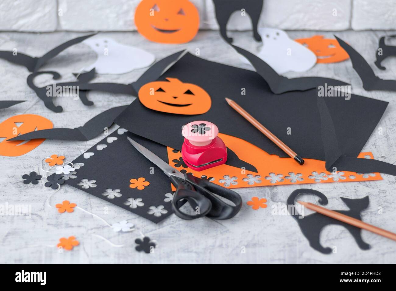 Preparation for Halloween Decoration for the holidays, cutting from colored  paper on a white brick wall. orange and black colored paper, scissors,  pencils, figured hole punch Soft focus Stock Photo - Alamy