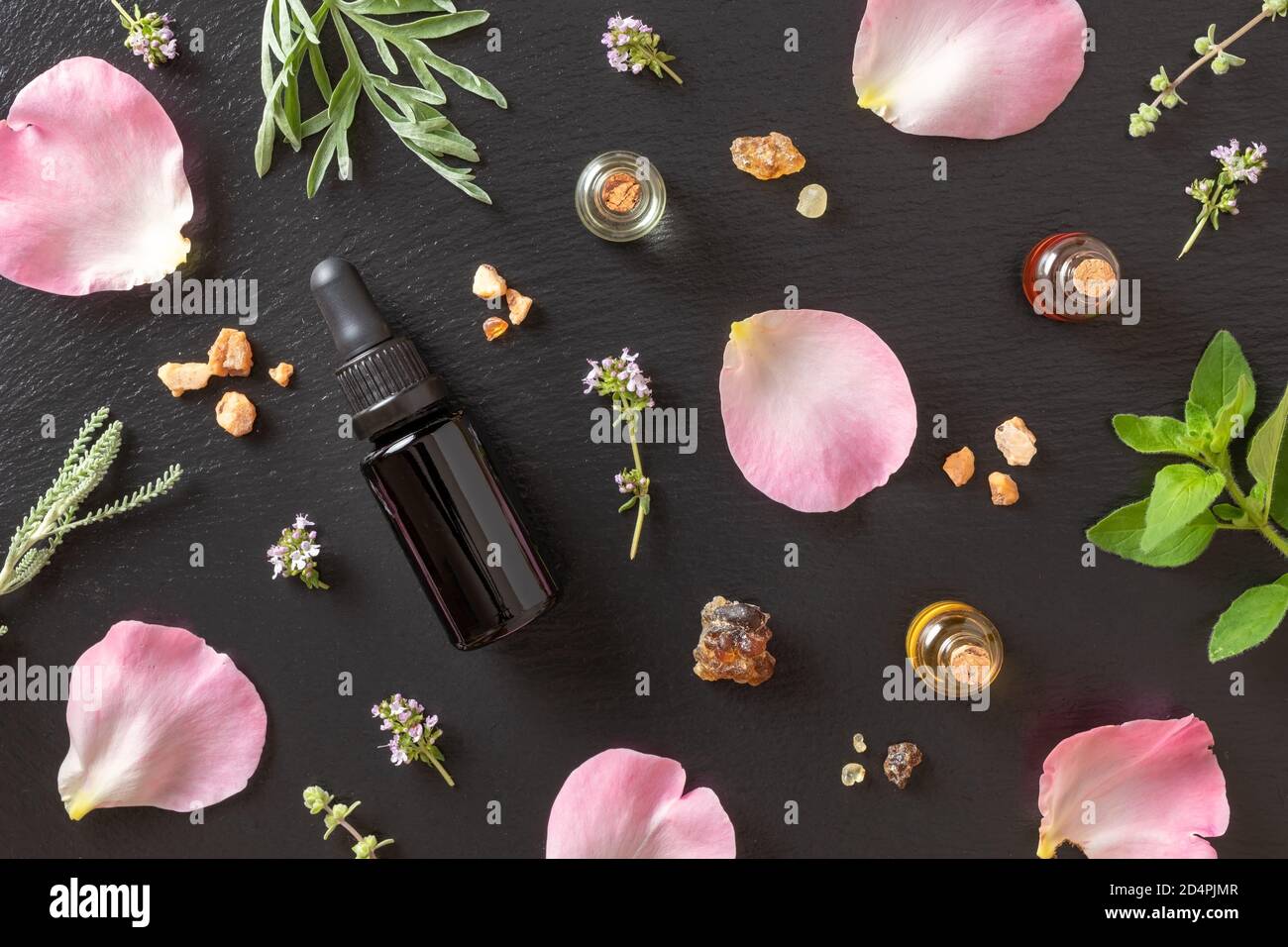Bottles of essential oil with frankincense, rose petals, oregano