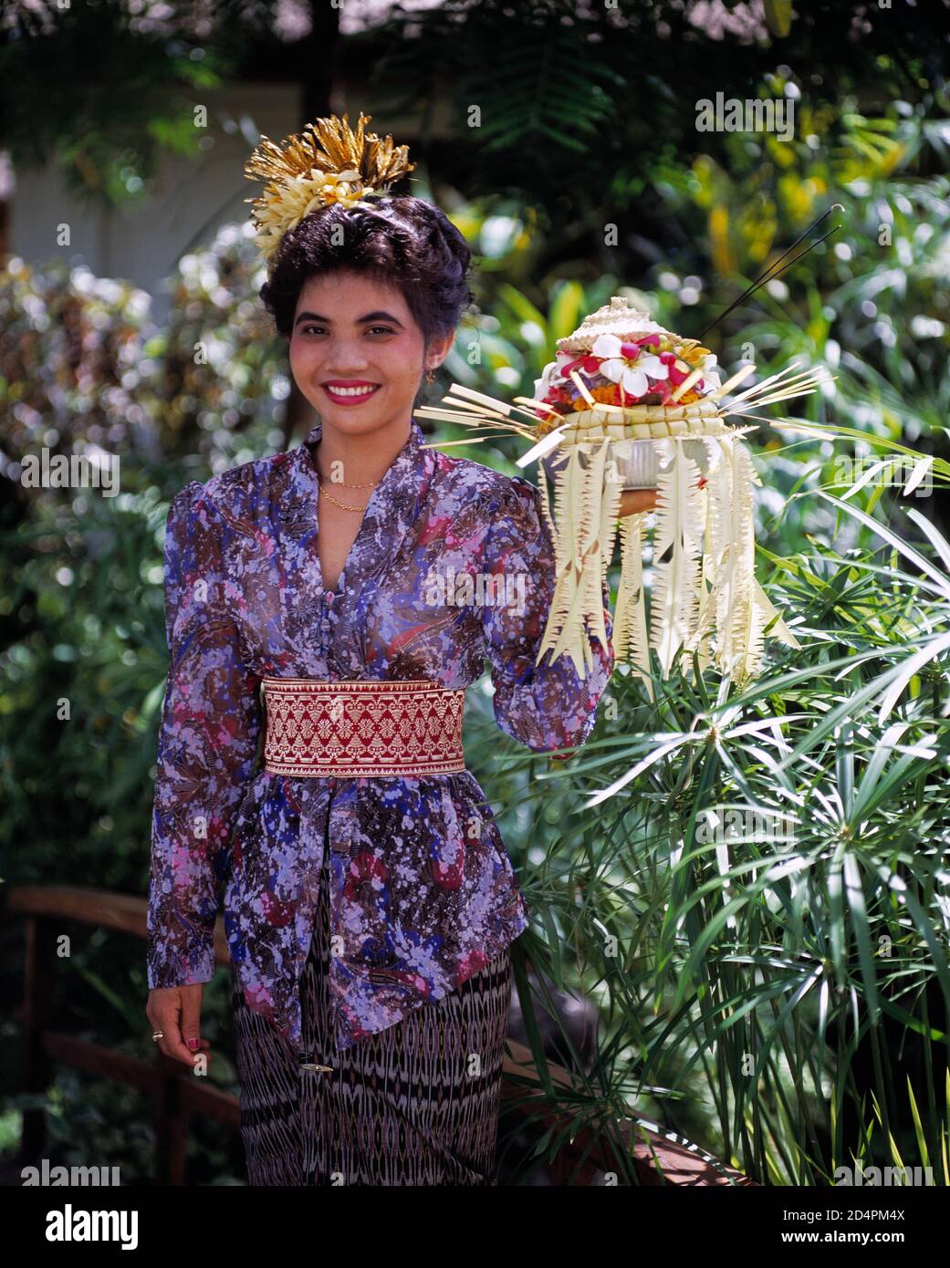 Indonesia. Bali. Local woman in traditional dress carrying offerings. Stock Photo