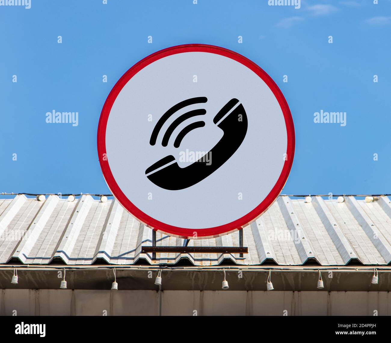 A Circle billboard with icon a calls phone, is installed on a roof. Board of telecommunication service. Stock Photo