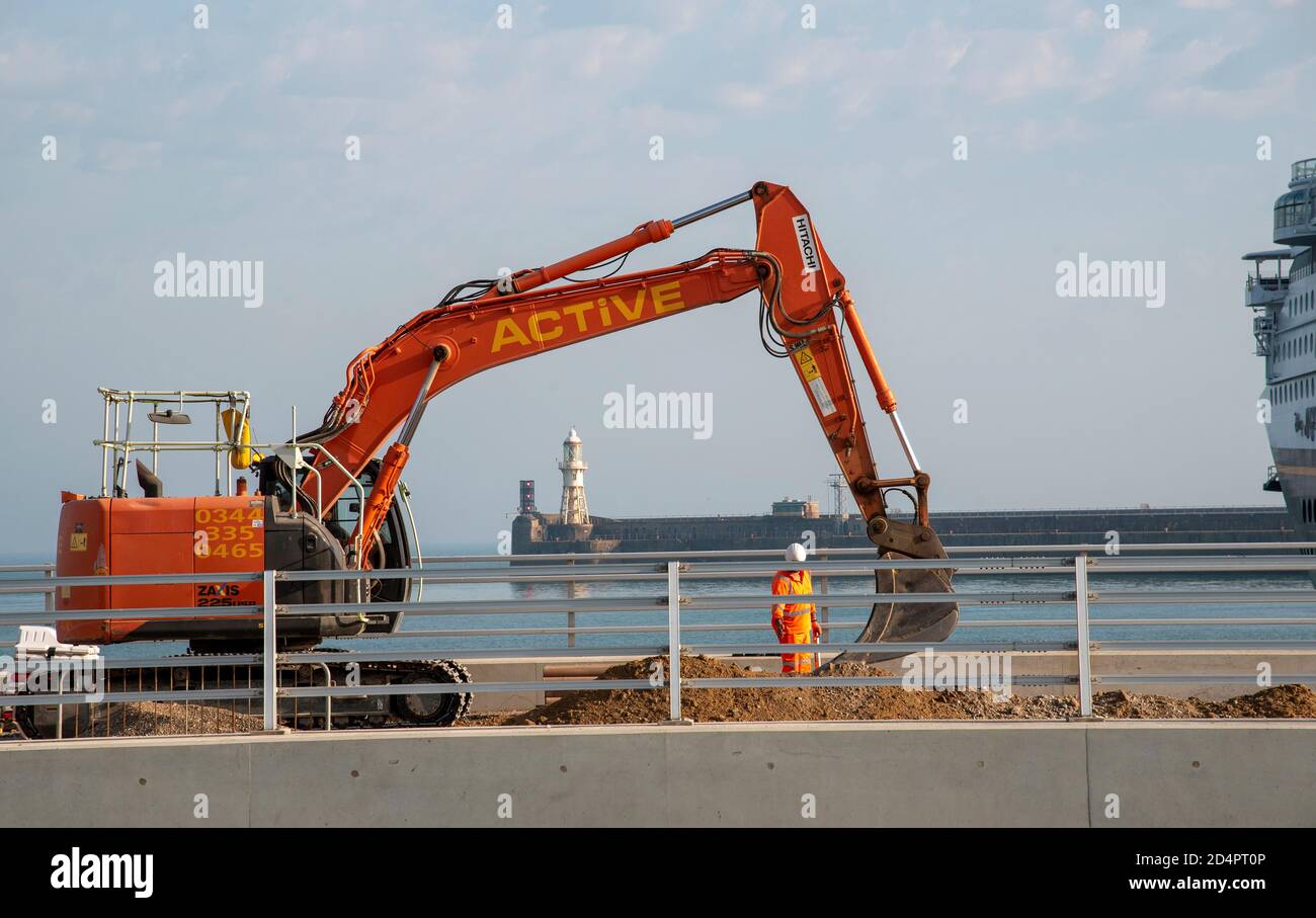 Dover, Kent, England, UK. 2020.  Civil engineering work being carried out at Dover Harbour using a excavator with a backdrop of the harbour entrance. Stock Photo