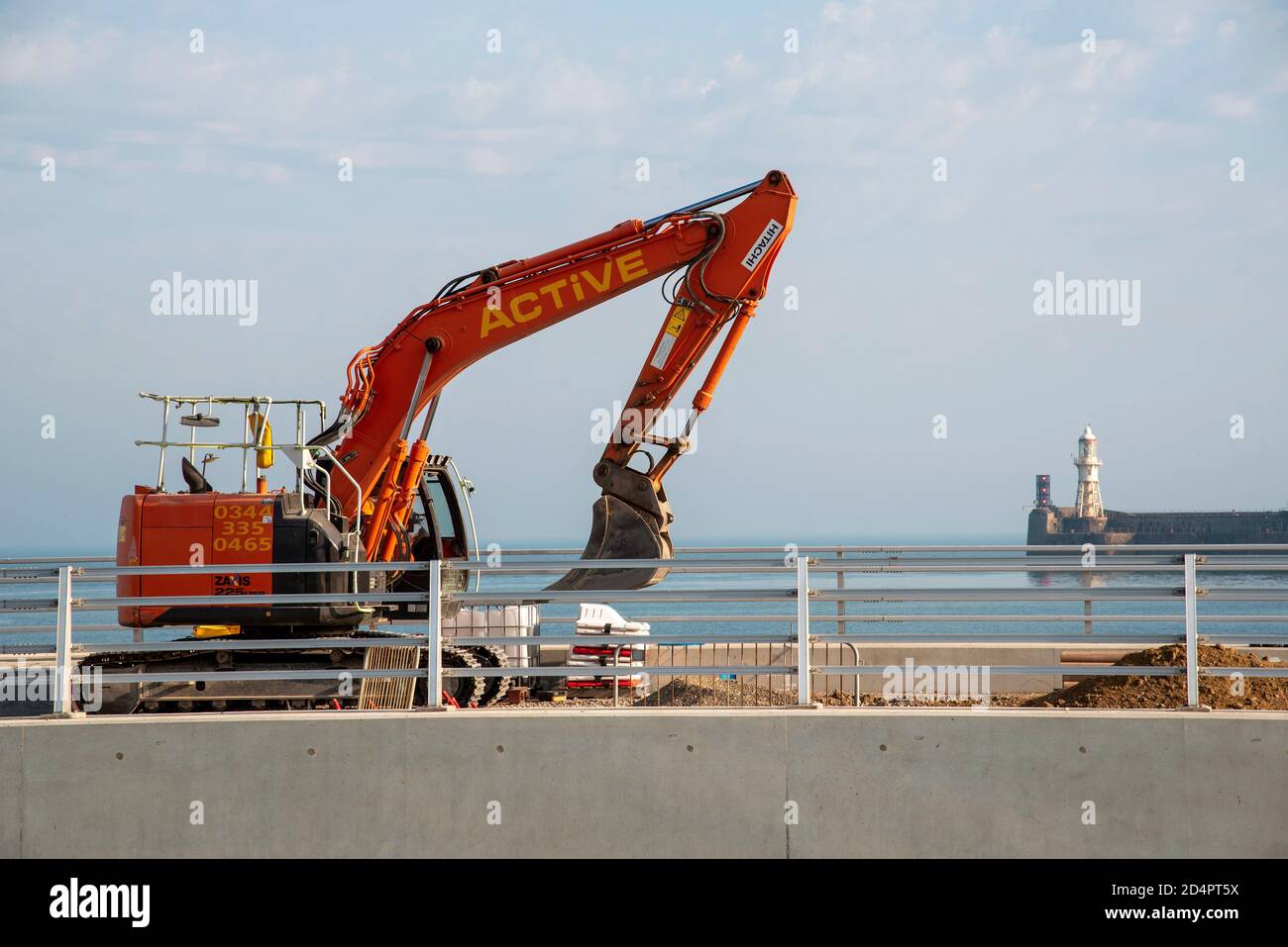 Dover, Kent, England, UK. 2020.  Civil engineering work being carried out at Dover Harbour using a excavator with a backdrop of the harbour entrance. Stock Photo