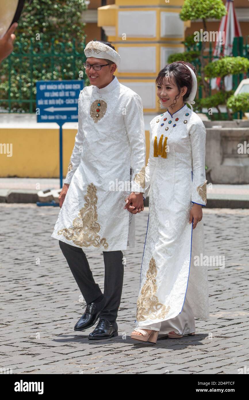 Ho Chi Minh, Vietnam. August 07, 2017: Vietnamese married couple in white dress walking on the streets of Ho Chi Minh City in Vietnam. Smiling outdoor Stock Photo