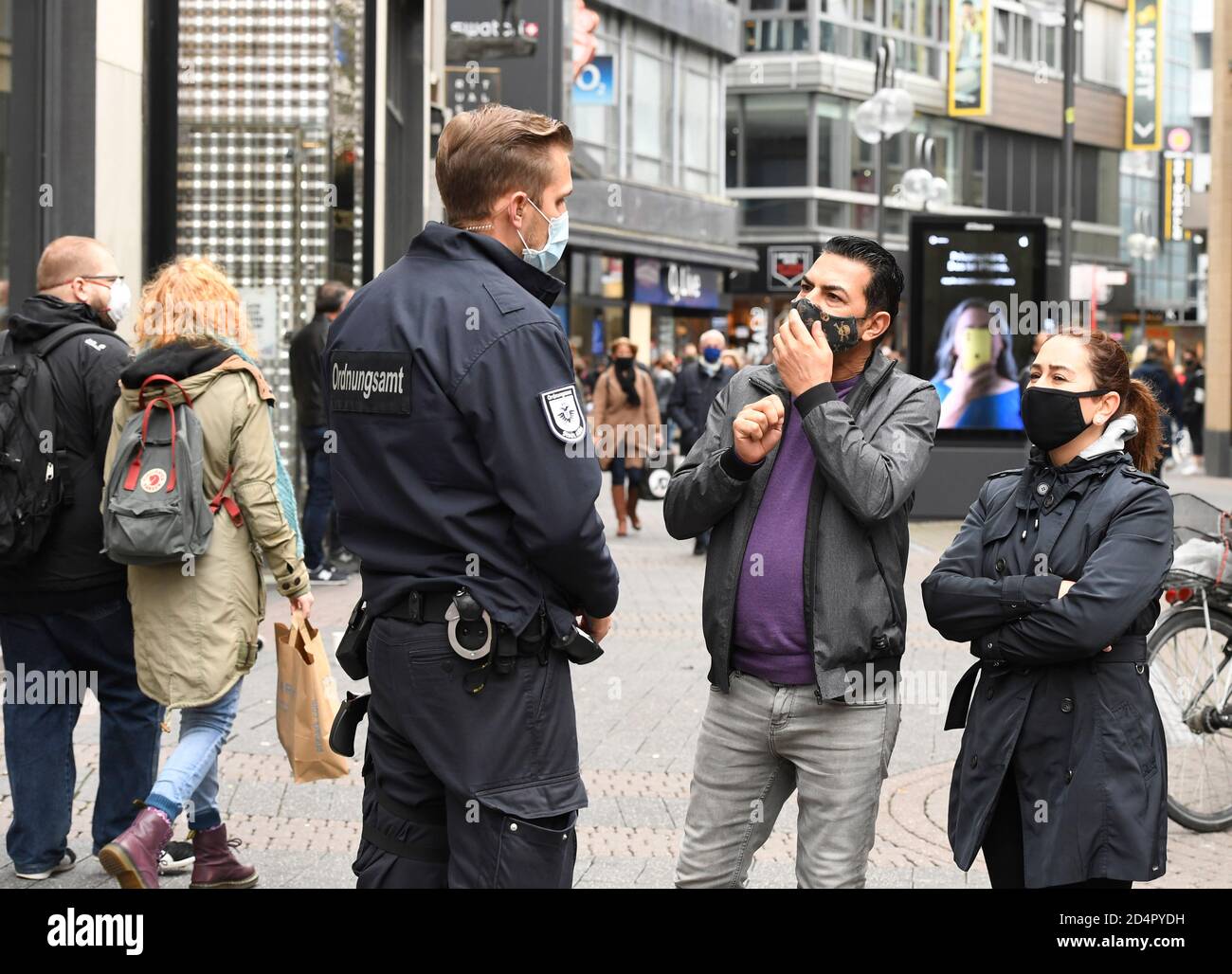 Cologne, Germany. 10th Oct, 2020. A city worker checks on Saturday to make sure pedestrians are in compliance with pandemic rules requiring they wear a mask in the German city of Cologne. Coronavirus numbers in Germany kept rising on Saturday, as new restrictions came into force despite the resistance of protesters against what they say is a government-sponsored 'campaign of fear.' Credit: Roberto Pfeil/dpa/Alamy Live News Stock Photo