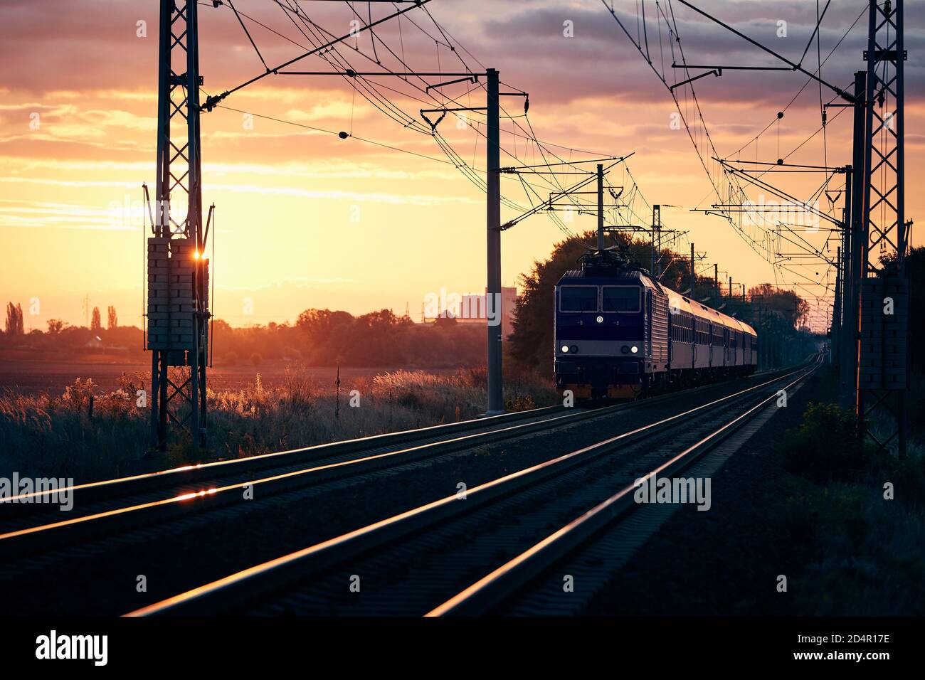 Passenger train of public transport on railroad track at beautiful sunrise. Stock Photo