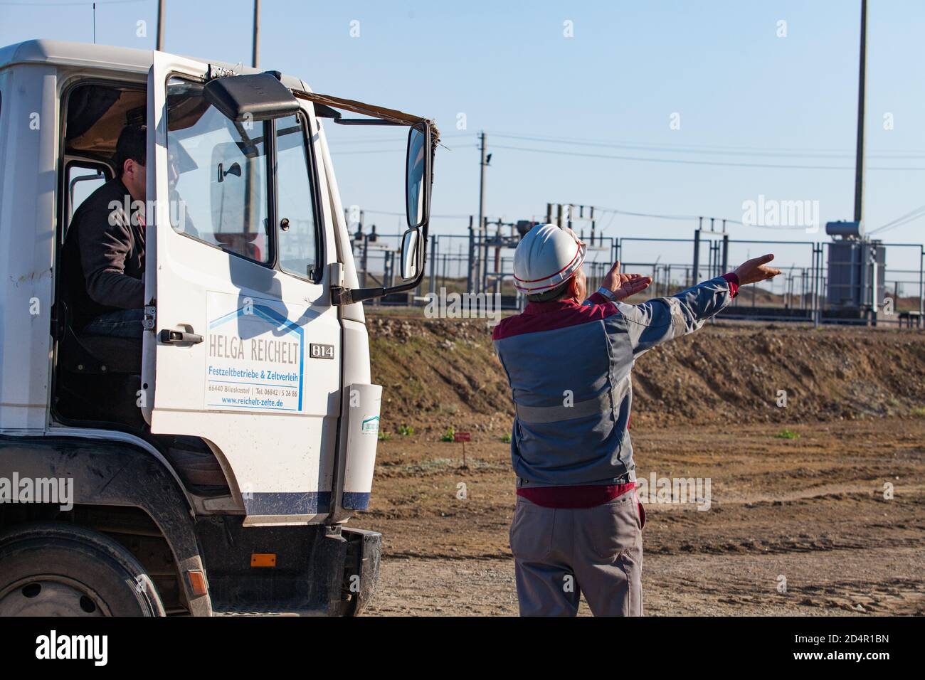 Aktobe region/Kazakhstan - May 04 2019: Phosphate fertilizers plant. Loading station. Worker show direction for truck driver. Stock Photo