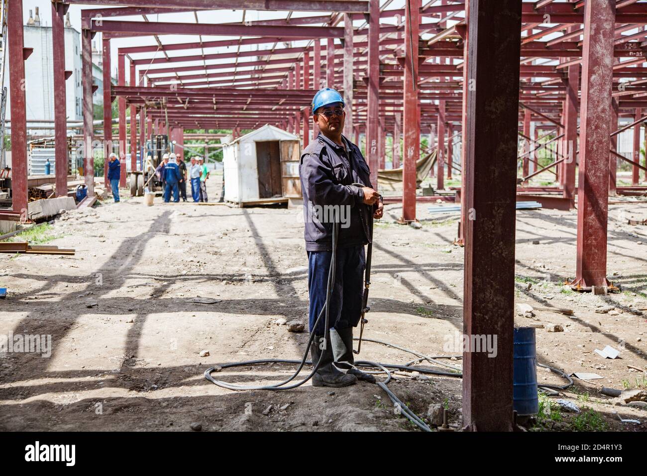 Shymkent, Kazakhstan: Construction of new industrial building of chemical pharmaceutical plant Santo. Welder worker on ground with ga Stock Photo