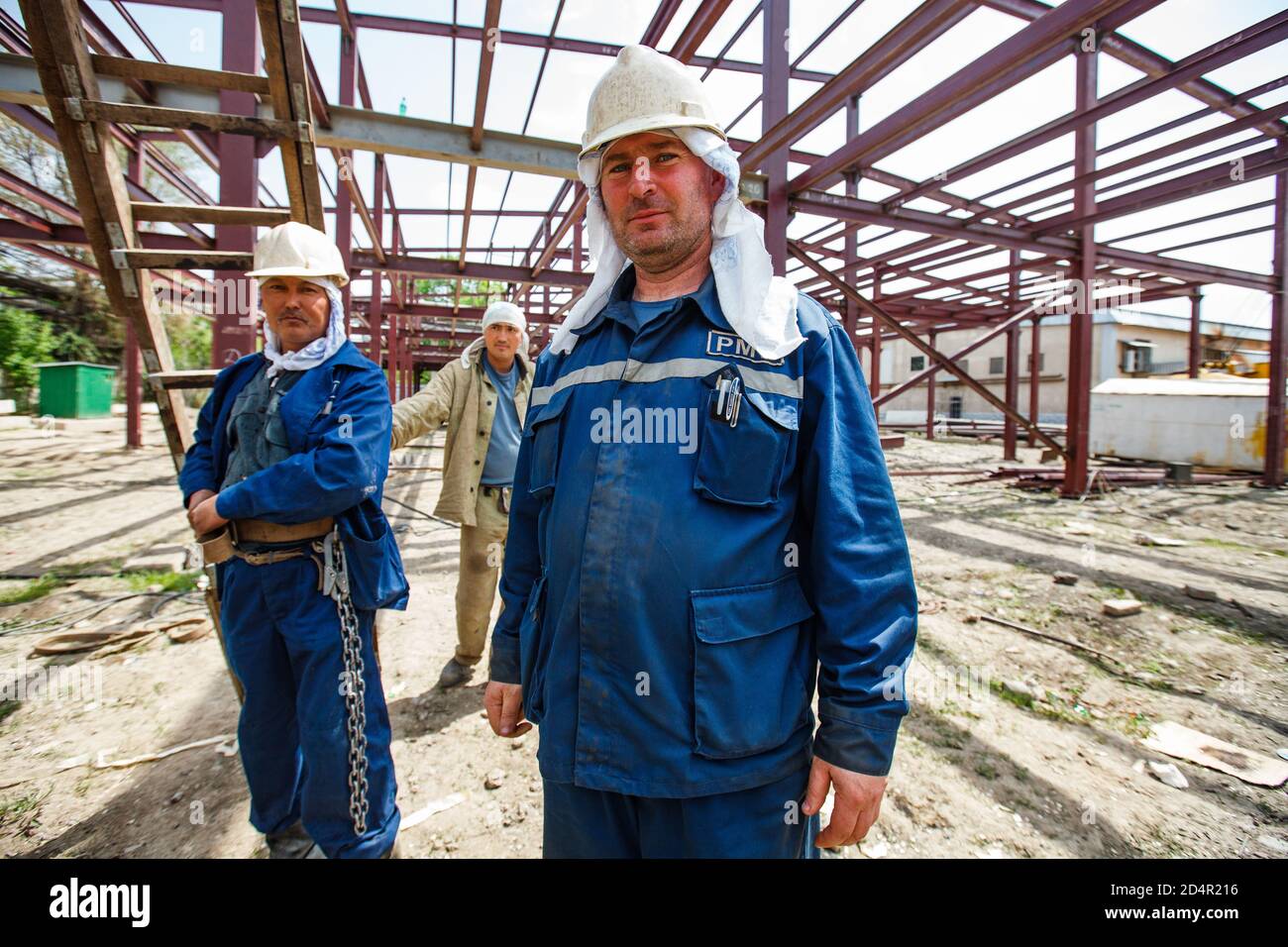 Shymkent/Kazakhstan - April 27 2012: Construction of new industrial building. Workers posing on the metal building structure background. Stock Photo