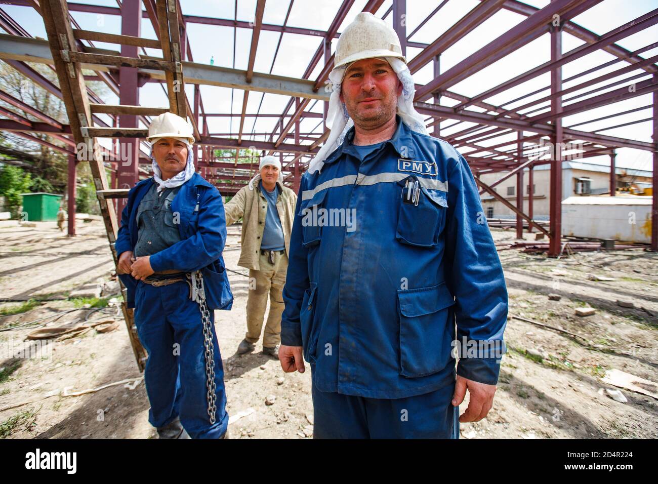 Shymkent/Kazakhstan - April 27 2012: Construction of new industrial building. Workers posing on the metal building structure background. Stock Photo