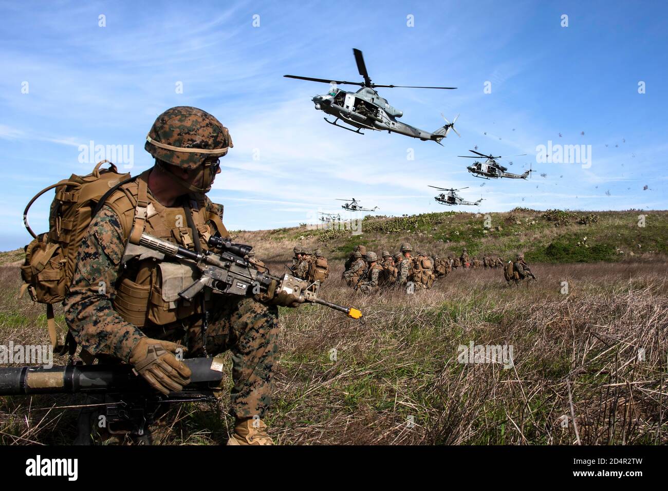 U.S. Marines with 2nd Battalion, 4th Marine Regiment, 1st Marine Division provide security for UH-1Y Venoms with Marine Light Attack Helicopter Squadron 469, Marine Aircraft Group 39, 3rd Marine Aircraft Wing, at a landing zone during Exercise Venom Storm on San Clemente Island, Calif., Jan. 15, 2020. Exercise Venom Storm demonstrated the Venom’s versatility in providing lethal options, whether operating from the sea or land. It’s ability to rapidly deploy from ship-to-shore, support ground forces with its own organic fire support and be armed and refueled at temporary sites is unmatched. The Stock Photo