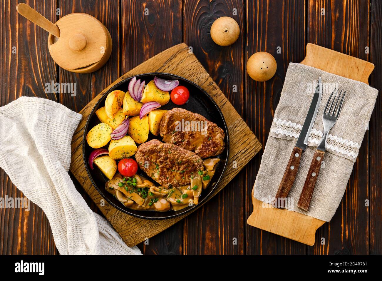 Top view of fried beef fillet with potato wedges served with fresh onion, tomato and honey mushrooms gravy Stock Photo