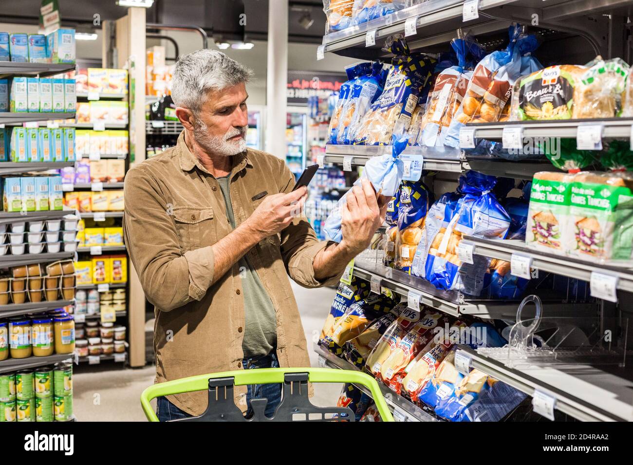 Man using an app on his smartphone in a supermarket Stock Photo - Alamy