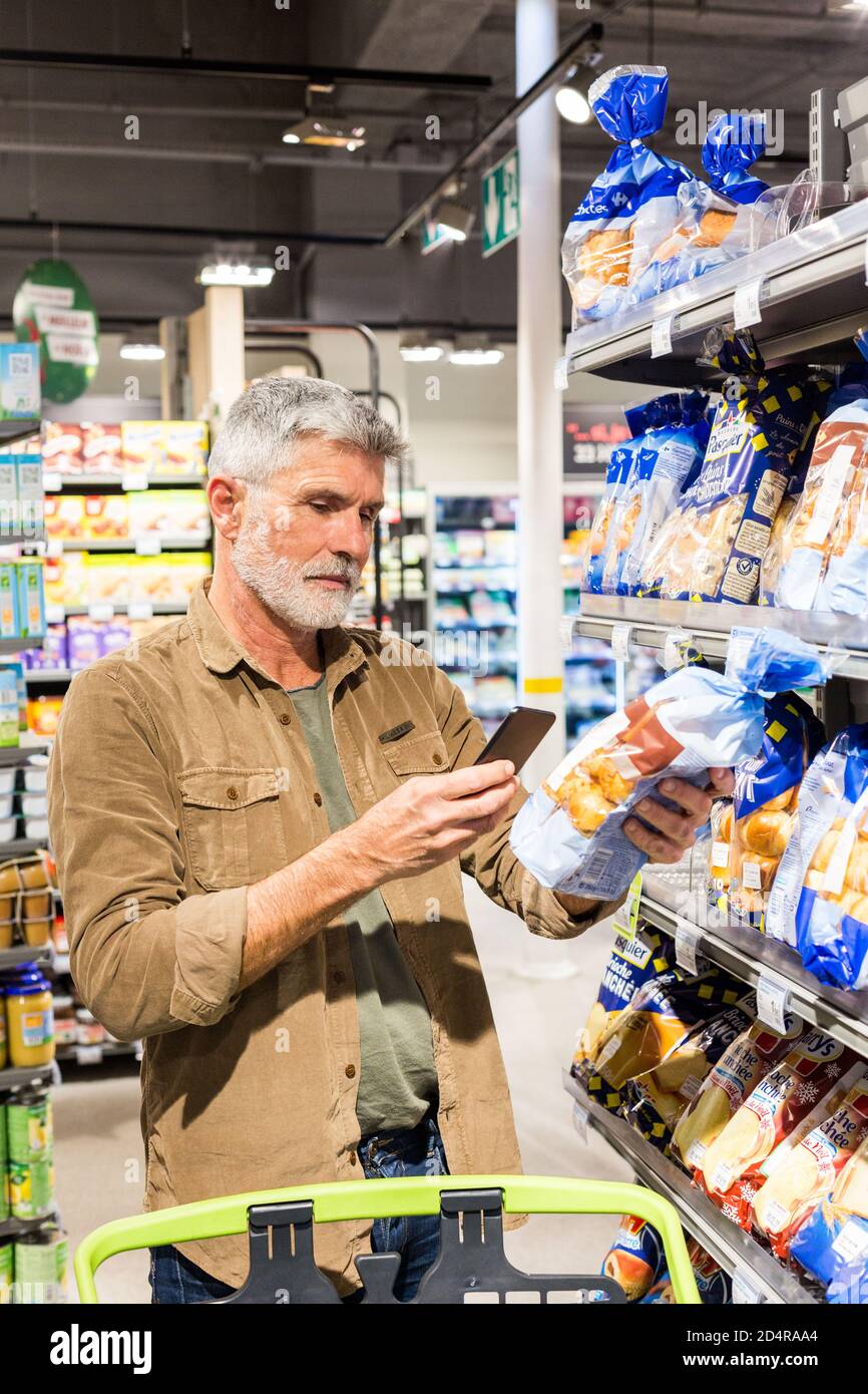 Man using an app on his smartphone in a supermarket Stock Photo - Alamy
