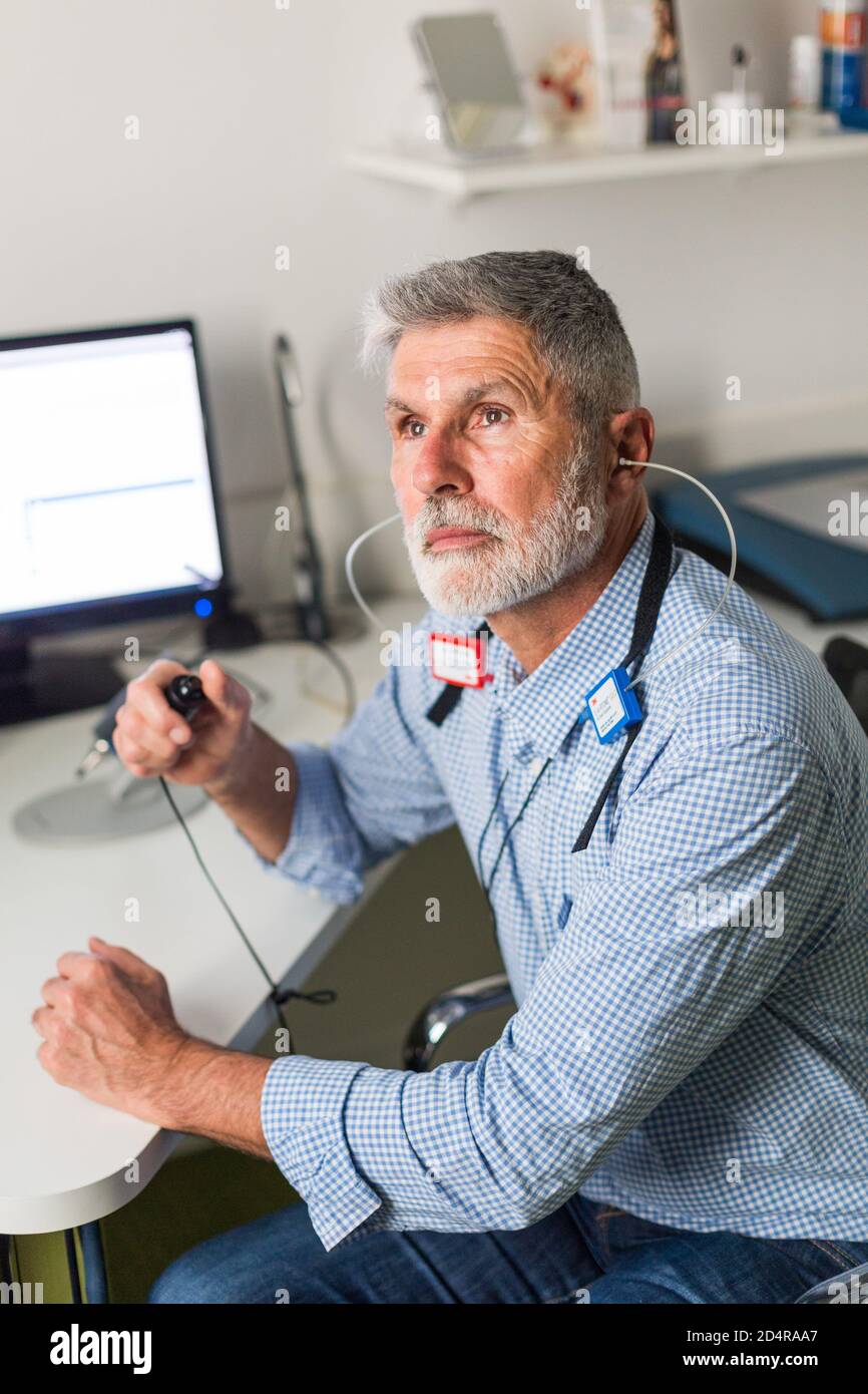 Man undergoing pure-tone audiometry test and hearing threshold measurement. Stock Photo