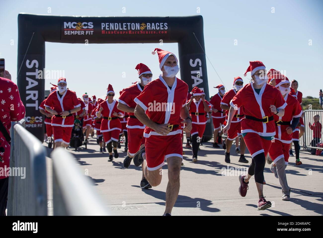 Service members and their families sprint from the starting line during the Santa Run at the Assault Craft Unit 5 compound on Marine Corps Base Camp Pendleton, California, Dec. 15, 2019. The Santa Run is part of the Hard Corps Race Series held by Marine Corps Community Services. MCCS is a comprehensive set of programs that support and enhance the operational readiness, war fighting capabilities, and life quality of Marines, their families, retirees and civilians. (U.S. Marine Corps photo by Lance Cpl. Andrew Cortez) Stock Photo
