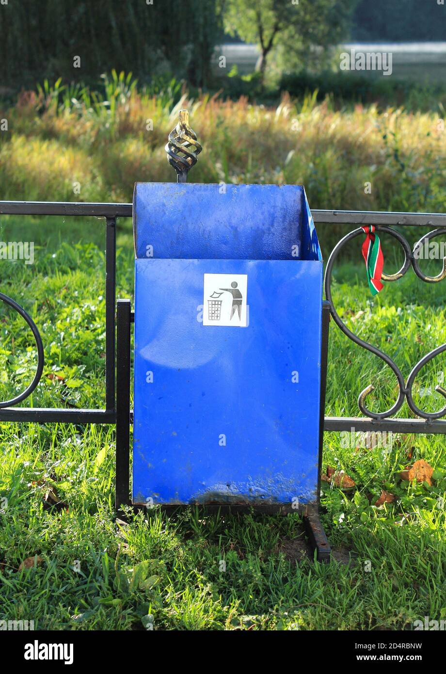 A large, metal, green garbage container and municipal waste, standing on a  dirt road near the fence and trees Stock Photo - Alamy