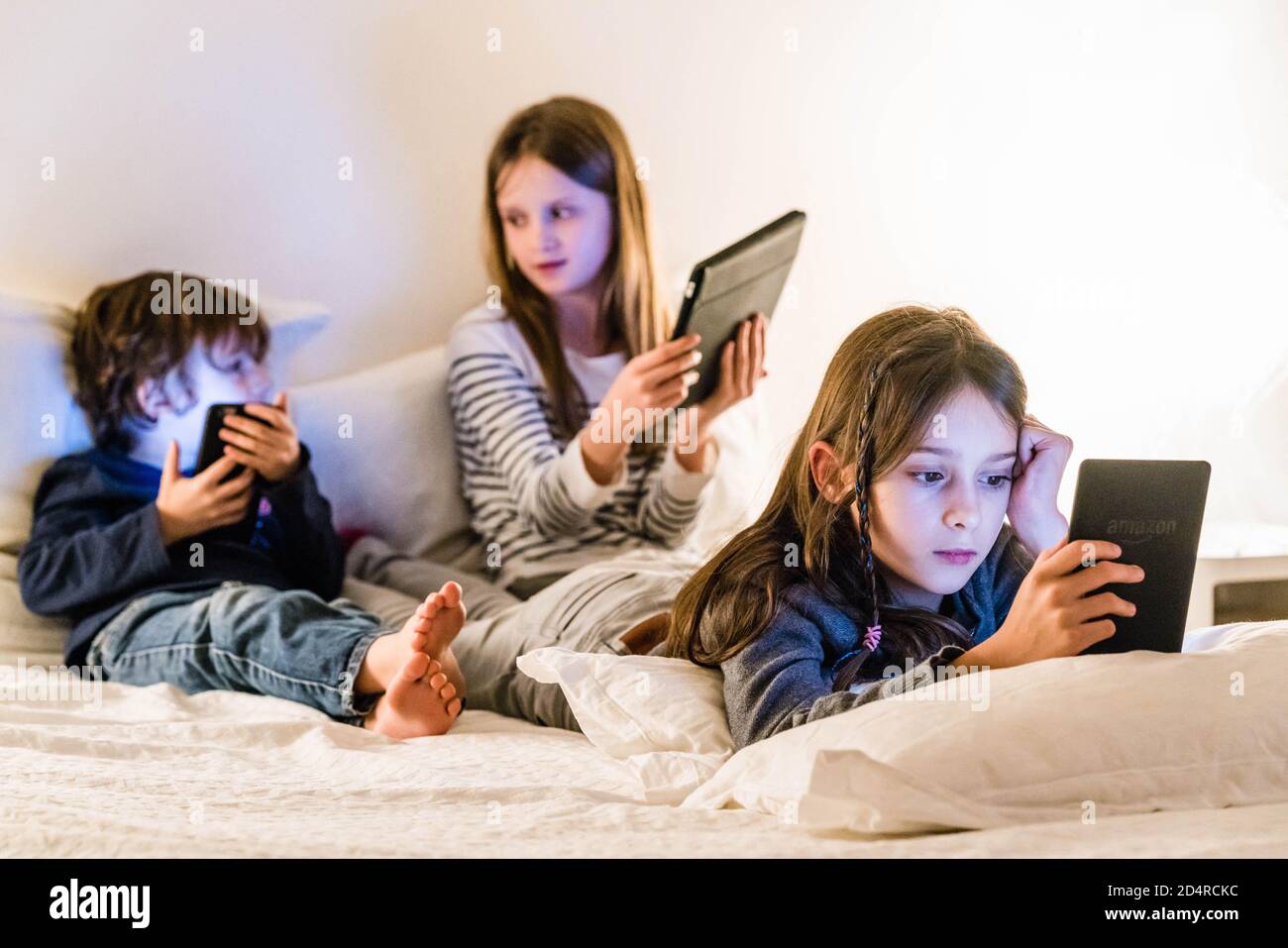 Children using a smartphone, a digital tablet and e-reader. Stock Photo
