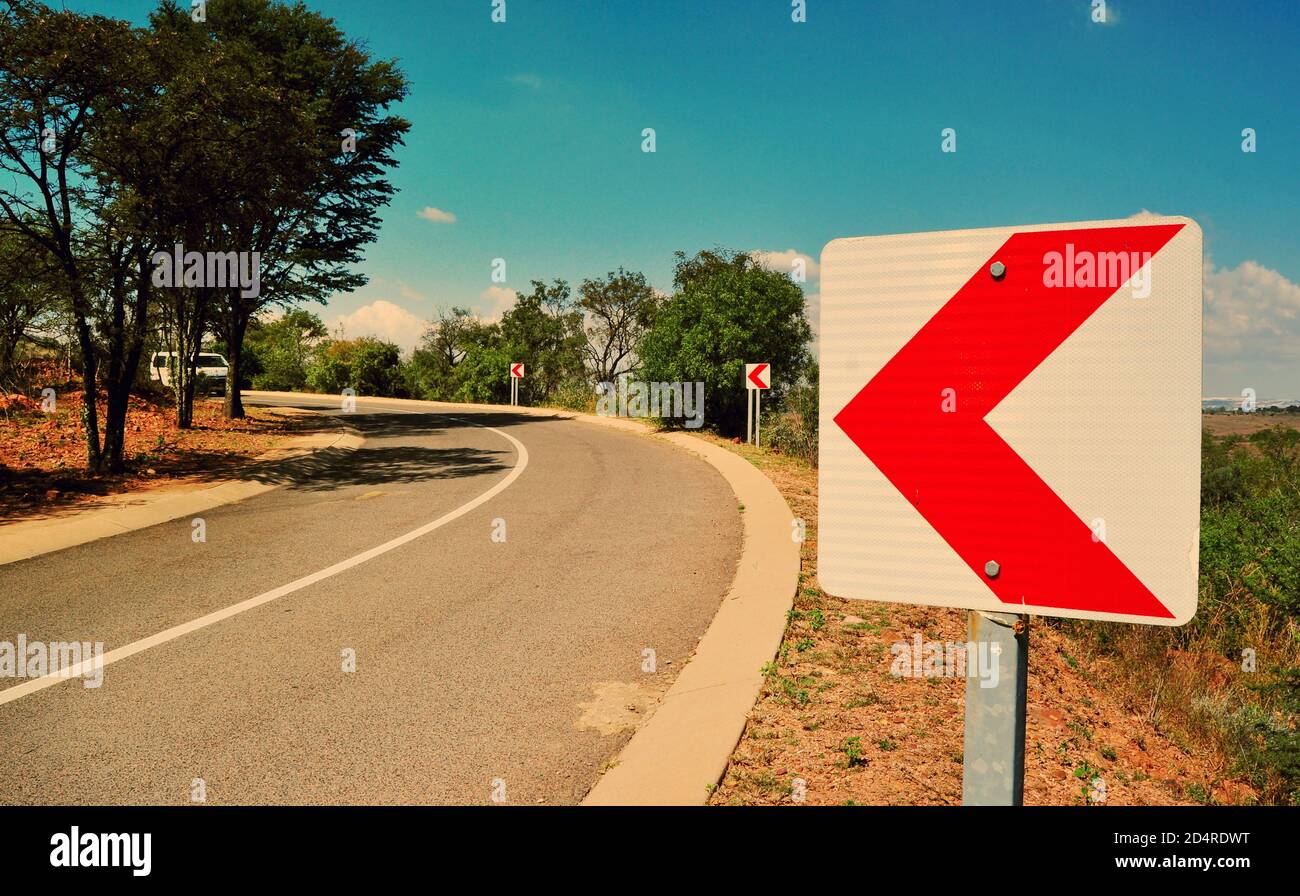Red chevron indicates sharp curve on the road, South Africa Stock Photo