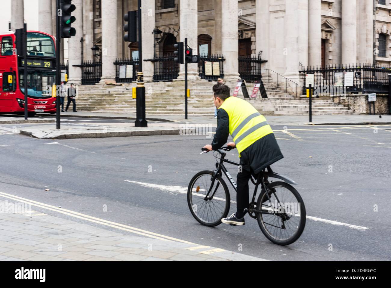 Cyclists with high visibility hi-vis jacket riding up London city road near Trafalgar Stock Photo