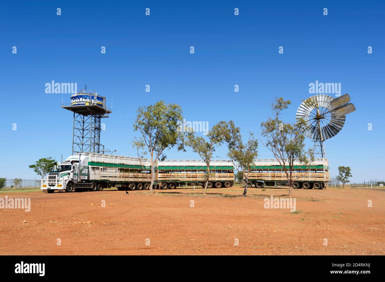 A road train or cattle truck is parked in front of a windvane and decorated water tower, Boulia, Queensland, QLD, Australia Stock Photo