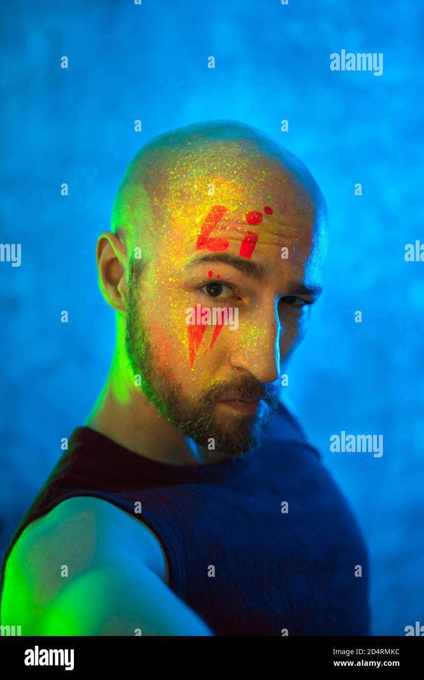 Portrait of calm young bald man with glowing body art. Beautiful fantastic drawing on skin. Stock Photo