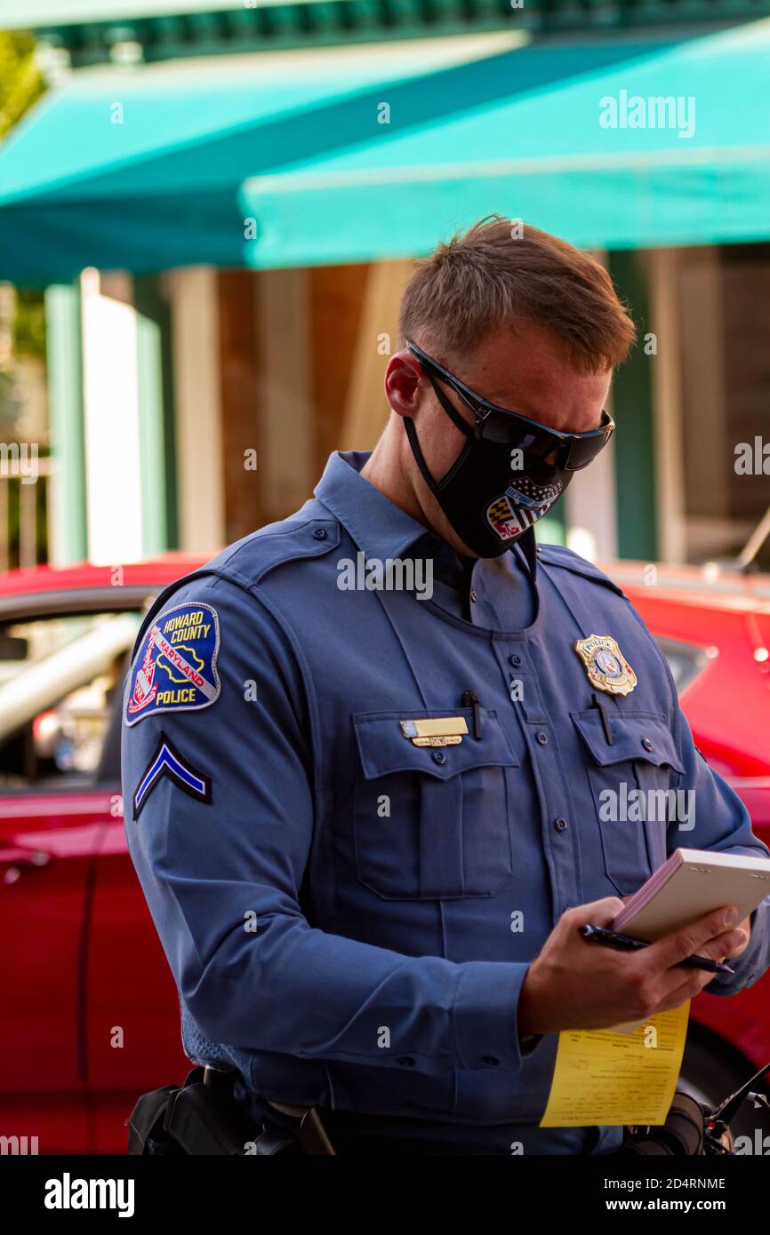 Ellicott City, MD, USA 10/07/2020: Close up image of a young caucasian police officer working in Howard County as he is writing a parking ticket for a Stock Photo