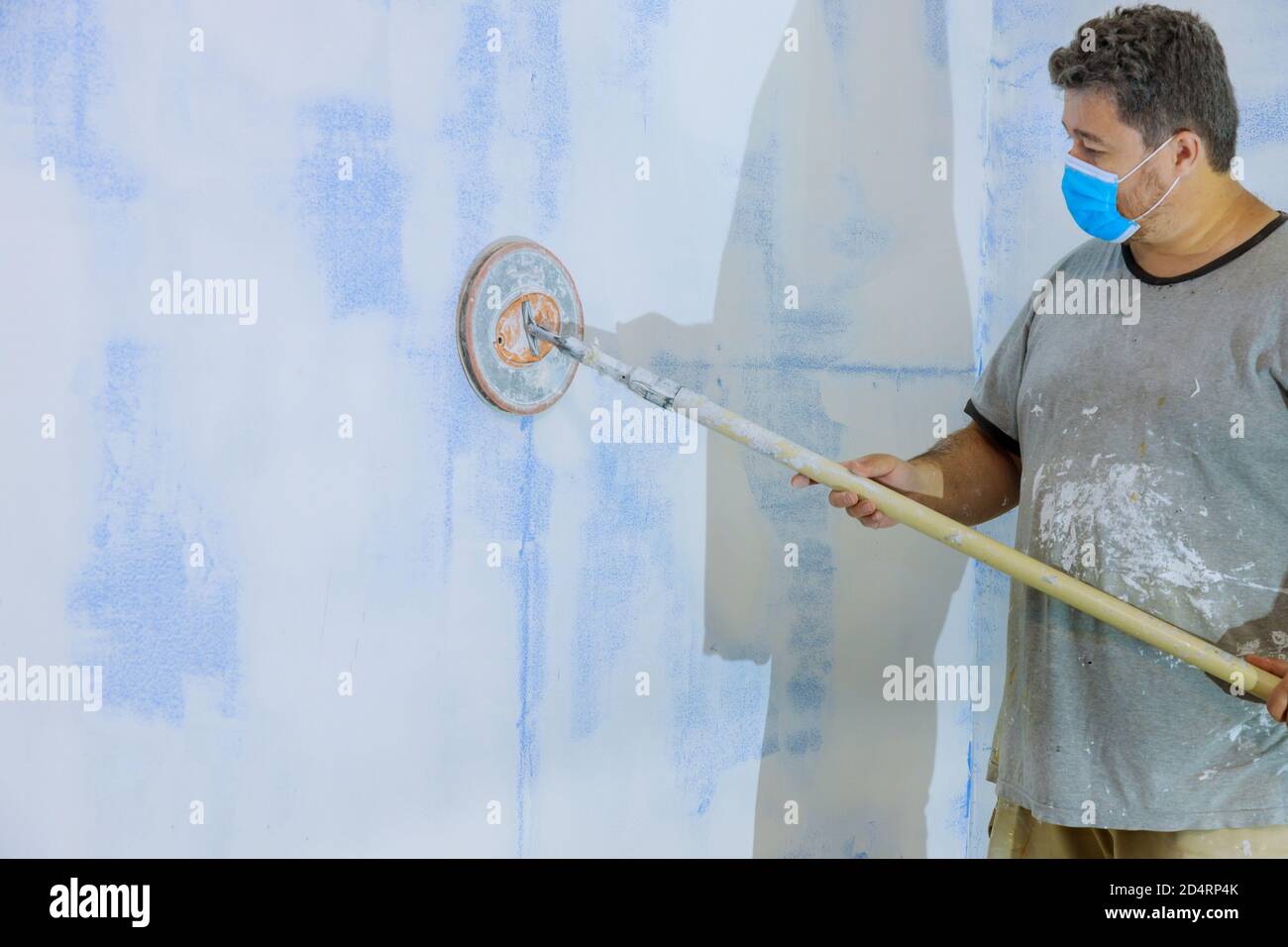 Worker smoothing and finishing wall with sanding the plaster