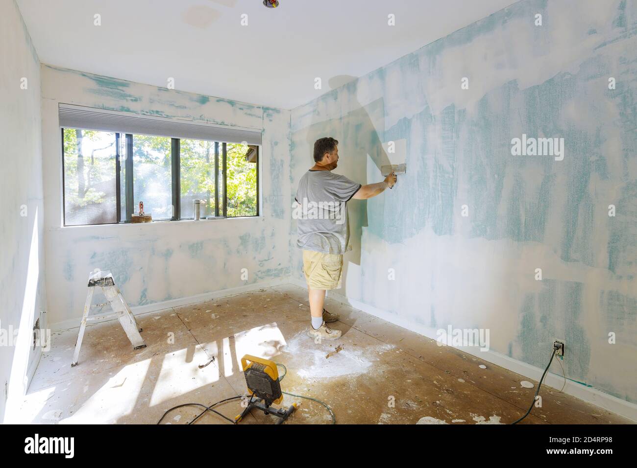 Worker puttied wall using a paint spatula hand worker repairs gypsum plasterboard Stock Photo