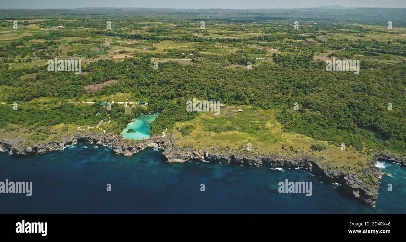 Green tropic forest at cliff sea bay with turquoise salt water lake aerial view. Amazing nature scenery of long-held tradition village with unique landmarks at Sumba Island, Indonesia, Asia Stock Photo