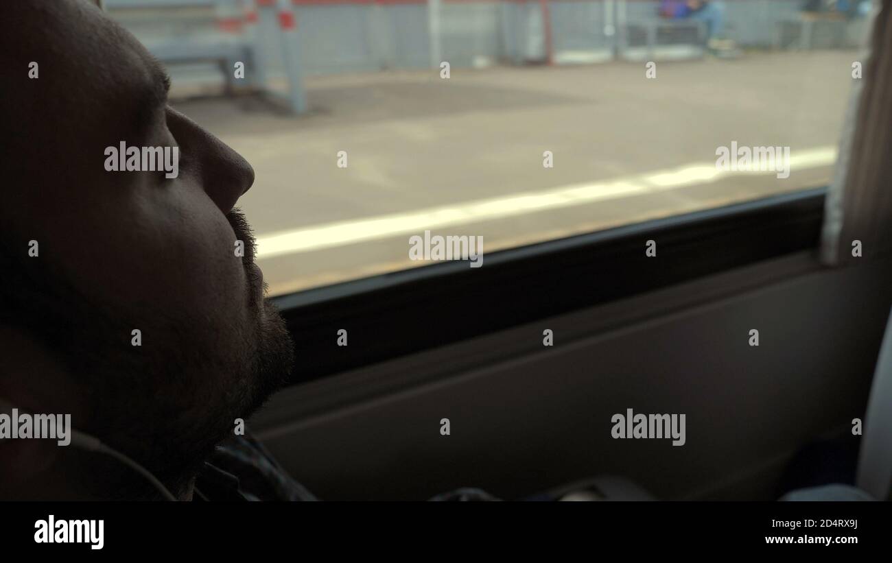 Long way. Man sleeping in the train. People standing behind the window. Stock Photo
