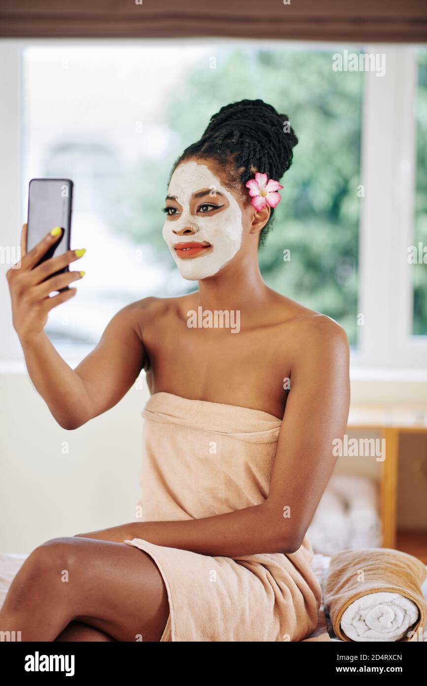 Woman with clay mask taking selfie Stock Photo