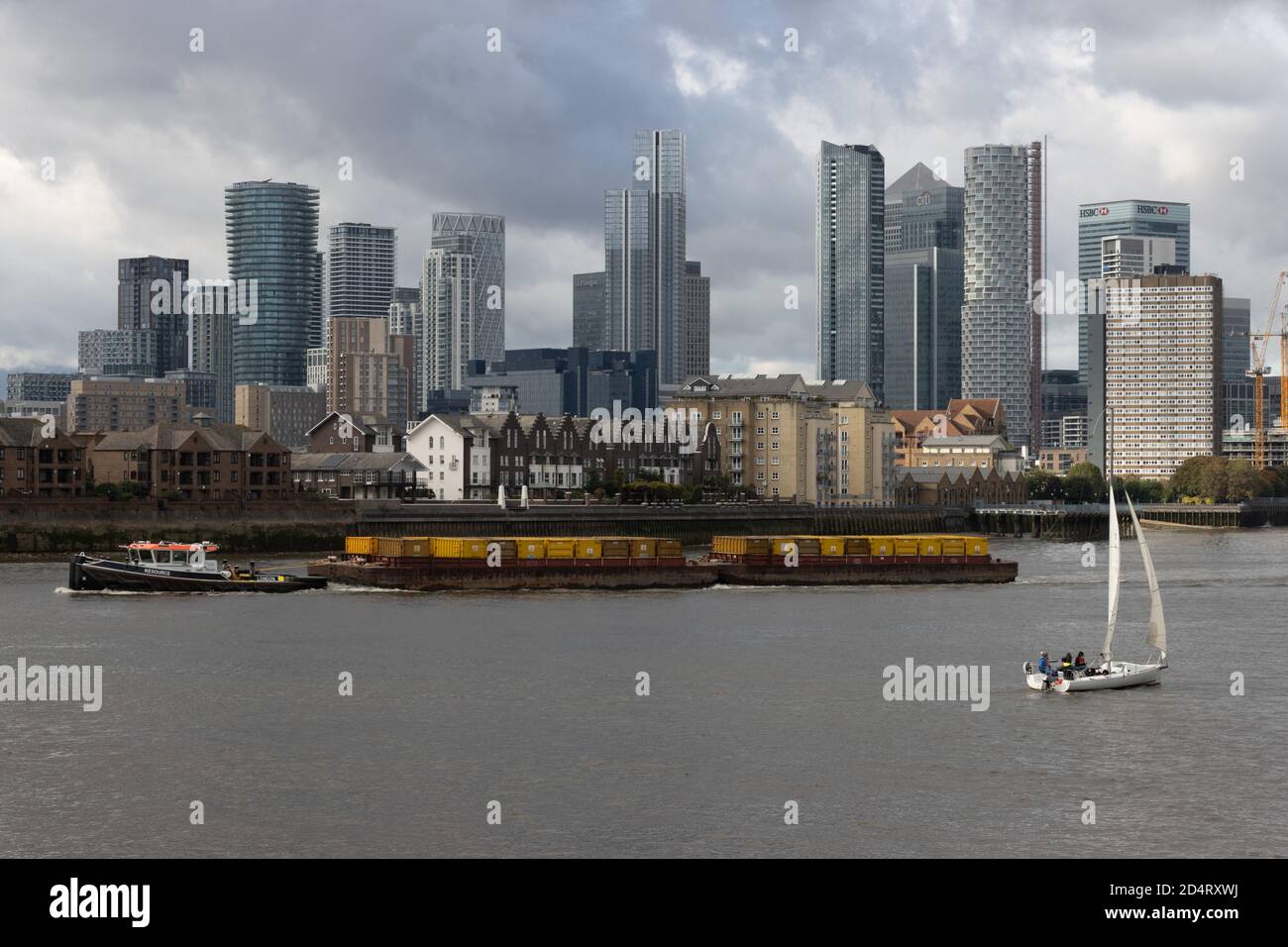Cargo vessels and sailing boat with Canary Wharf in background, London UK Stock Photo