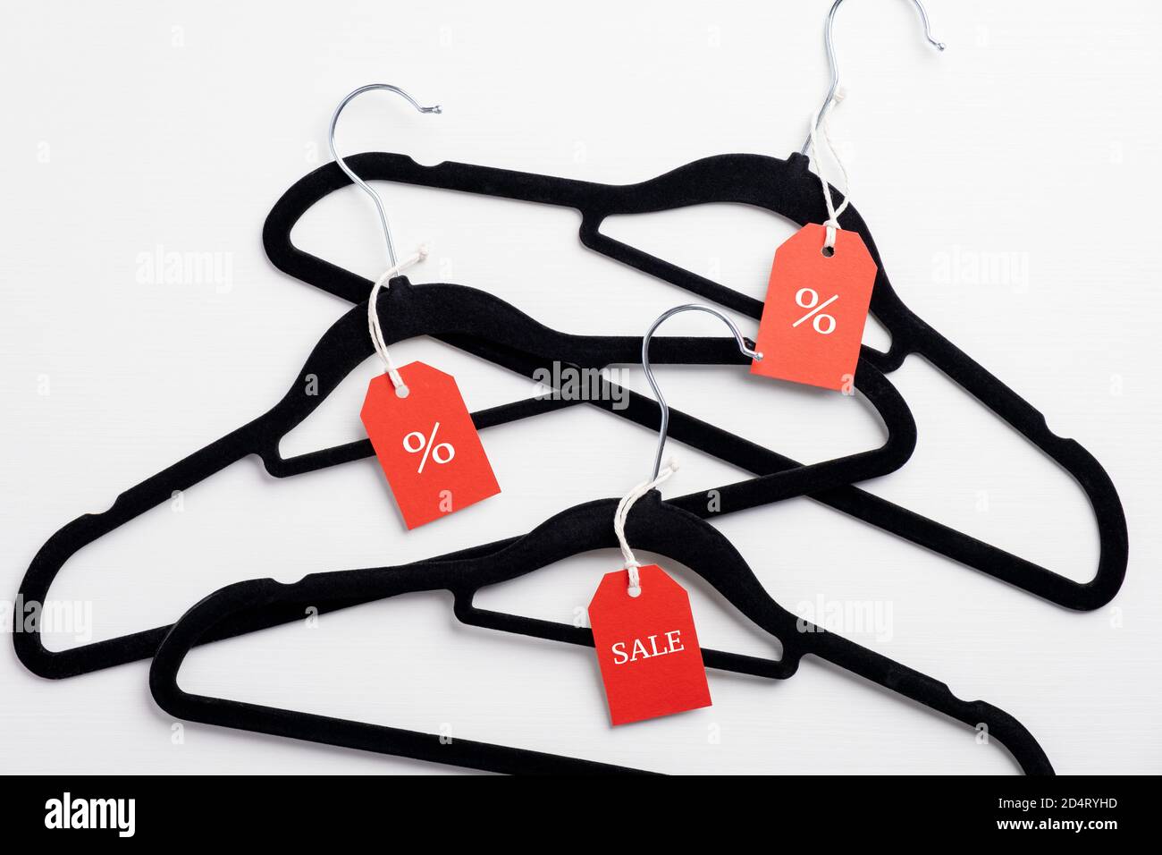 Black Friday sale, discount, outlet concept. Coat hangers with red label tags on white background. Flat lay, top view. Stock Photo