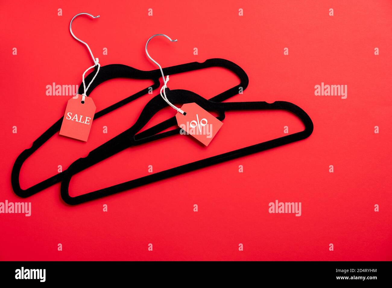 Two coat hangers on red background. Flat lay, top view. Black Friday sale, discount, outlet in fashion store concept. Stock Photo