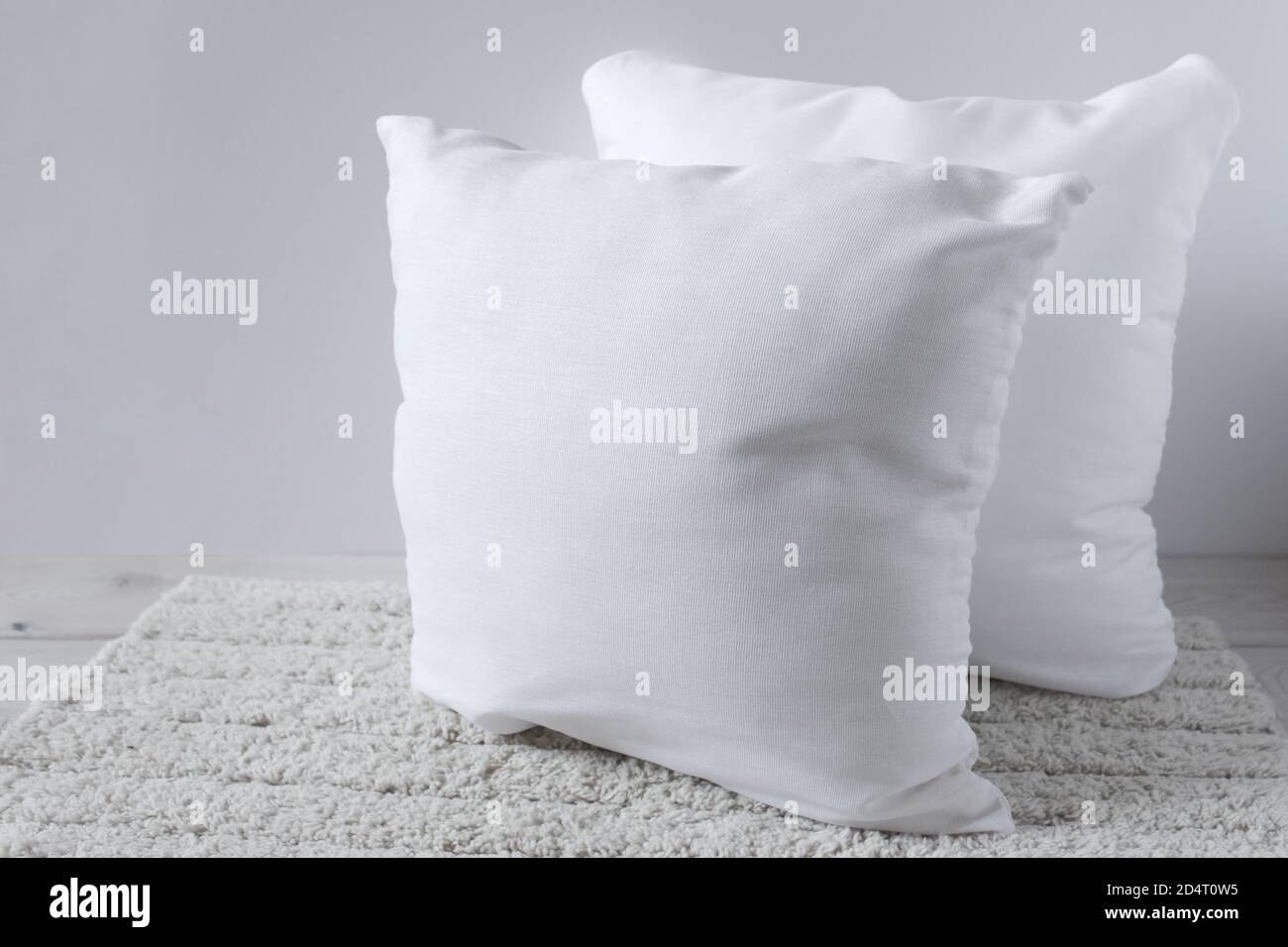 Two white pillows on a fluffy rug. Objects on a wooden surface. Stock Photo